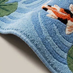 Close up of hand tufted wool rug pile showing carved water ripple texture and raised koi fish details