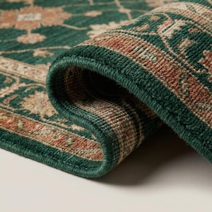 Close-up of hand knotted wool rug showing dense knot structure, soft wool fibers, and detailed floral weaving in green and beige tones
