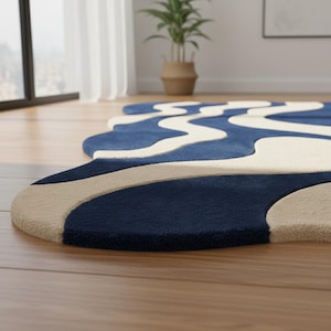 K&ouml;nnte beinhalten: Ein moderner Teppich mit einem einzigartigen, flie&szlig;enden Design. Der Teppich hat eine marineblaue Basis mit cremefarbenen und beigefarbenen wellenf&ouml;rmigen Mustern. Er liegt auf einem Holzboden, mit einem Blick auf ein Fenster und eine Topfpflanze im Hintergrund.