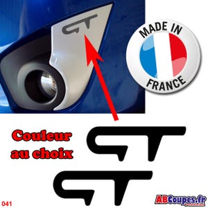 Op de afbeelding: Een close-up van een koplampassemblage van een auto met een zilveren accent en een zwart "GT"-logo. De afbeelding bevat ook een "Made in France"-embleem en de tekst "Couleur au choix".