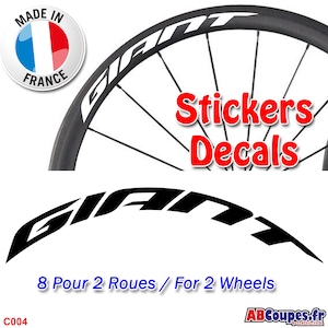 Può includere: Adesivi per ruote di bicicletta Giant in bianco e nero con la scritta "Stickers Decals". Gli adesivi sono progettati per due ruote e sono fabbricati in Francia. La ruota è nera con scritte bianche.