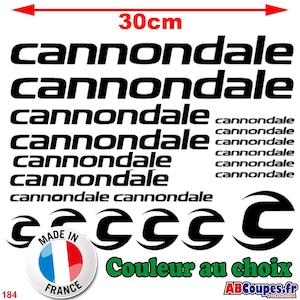 May include: A collection of black Cannondale decals and logos, with the text "Cannondale" repeated multiple times. The image includes a "Made in France" sticker and the text "Couleur au choix". The total width is 30cm.