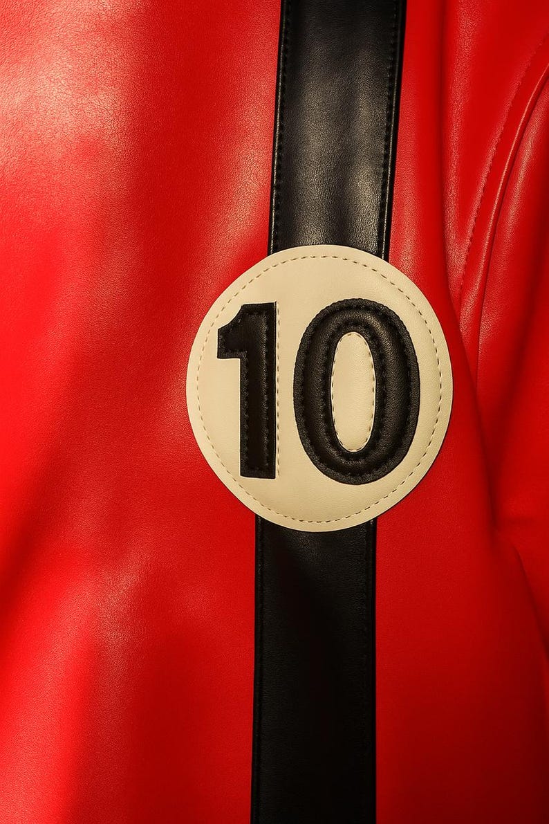 May include: Close-up of a red leather jacket with a black stripe and a white circular patch. The patch features the number 10 in black. The jacket has a smooth texture and a sporty design.