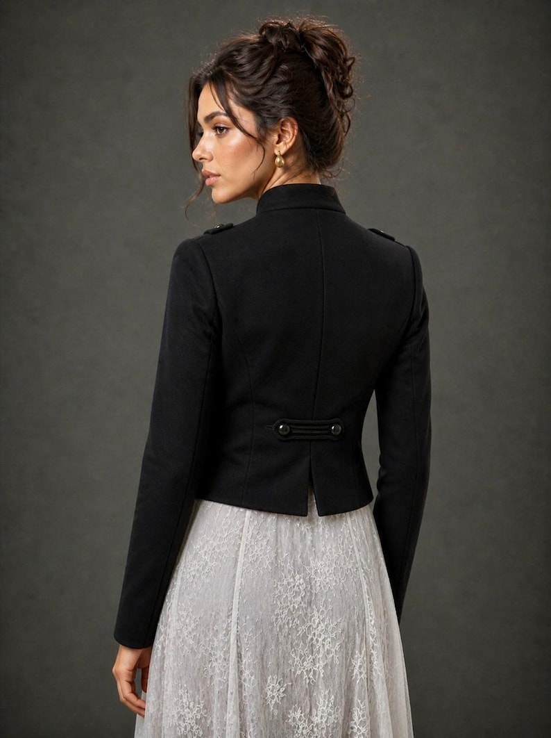 May include: A black jacket with a high collar and button details. The jacket has a tailored fit and is paired with a white lace skirt. The image is set against a dark gray background.