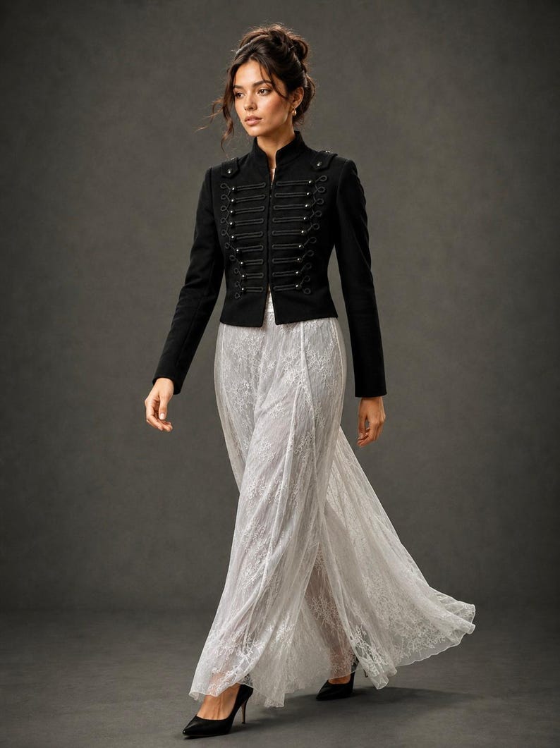 May include: A black military-style jacket with decorative silver buttons and a high collar. The jacket is paired with a flowing, white lace skirt. The outfit is completed with black high-heeled shoes, creating an elegant ensemble.