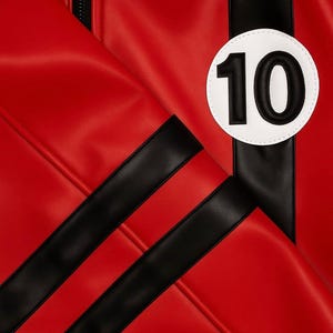 May include: Close-up of a red jacket with black stripes and a white circle with the number 10 in black. The jacket has a zipper and is made of a smooth material.