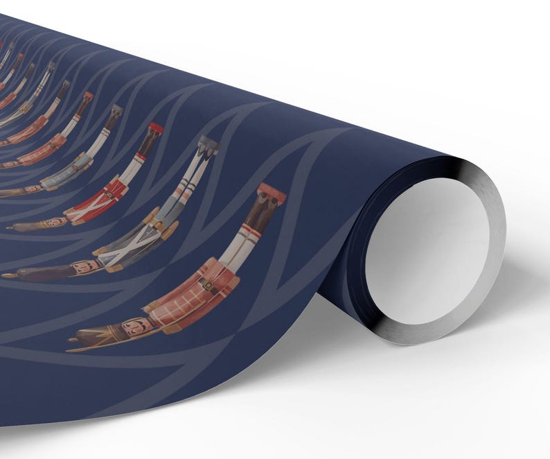 May include: A roll of wrapping paper featuring a repeating pattern of nutcracker figures in red, white, and brown uniforms. The nutcrackers are arranged in a curved, rhythmic sequence against a solid dark navy blue background with light blue lines.