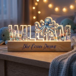May include: A wooden night light spelling "WILLIAM" in white, with a blue octopus design and ocean-themed details. The base is inscribed with "Blue Ocean Dreams". The light is suitable for a child's room.