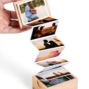 May include: A wooden photo box with a series of attached photos, each displaying a different image. The photos are in a zig-zag pattern, with the top photo held in place by a wooden frame. The images depict couples in various outdoor settings.