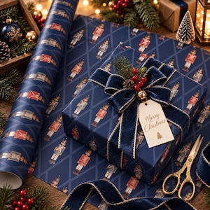 May include: A navy blue gift box wrapped in paper featuring a repeating nutcracker pattern, adorned with a dark blue velvet ribbon, a small pine sprig with red berries, and a cream-colored gift tag with the text Merry Christmas and a tree icon.