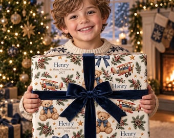 May include: A rectangular gift box wrapped in cream-colored paper featuring a repeating pattern of teddy bears, vintage airplanes, pine cones, and holly. The text Henry Merry Christmas 2027 is printed on the paper, tied with a dark blue velvet ribbon.