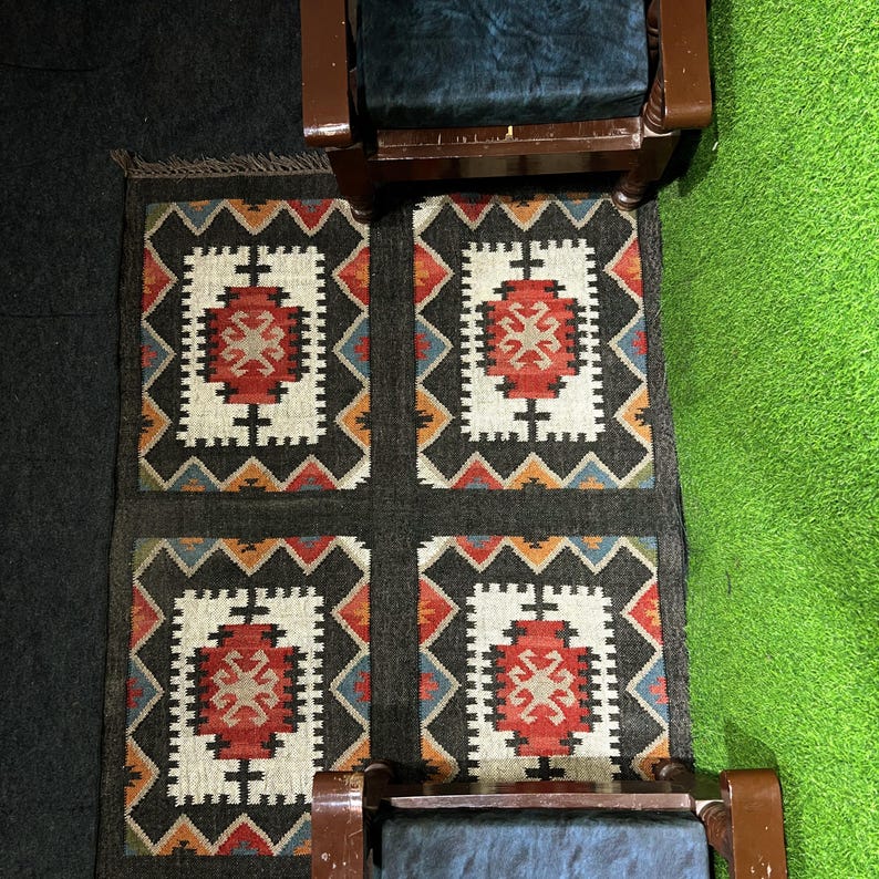Rustic black tribal flatweave rug handwoven by artisans in Jaipur India, bold southwestern geometric medallion pattern in rust red ivory and teal