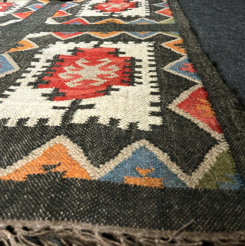 Handmade black southwestern area rug with bold geometric pattern in multicolor rust ivory teal and orange, eco friendly wool jute flatweave