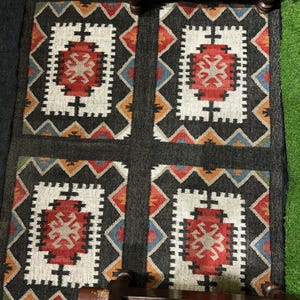 Black wool jute area rug with aztec geometric medallion design in rust burgundy and ivory white, handwoven with natural fringe, living room rug