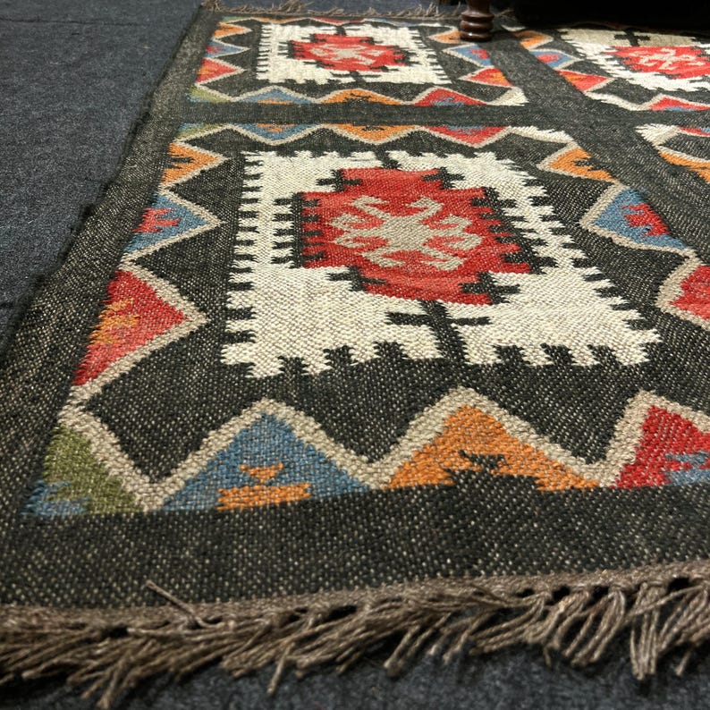 Dark charcoal geometric tribal rug with cream center medallions and rust red accent, handwoven flatweave wool jute, boho farmhouse decor