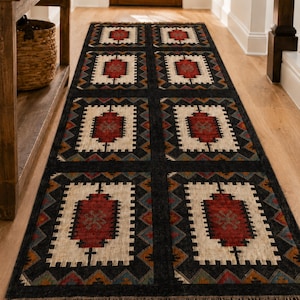 Overhead shot of black geometric dhurrie rug with repeating tribal square medallions in ivory rust and teal, natural fringe edges, custom size