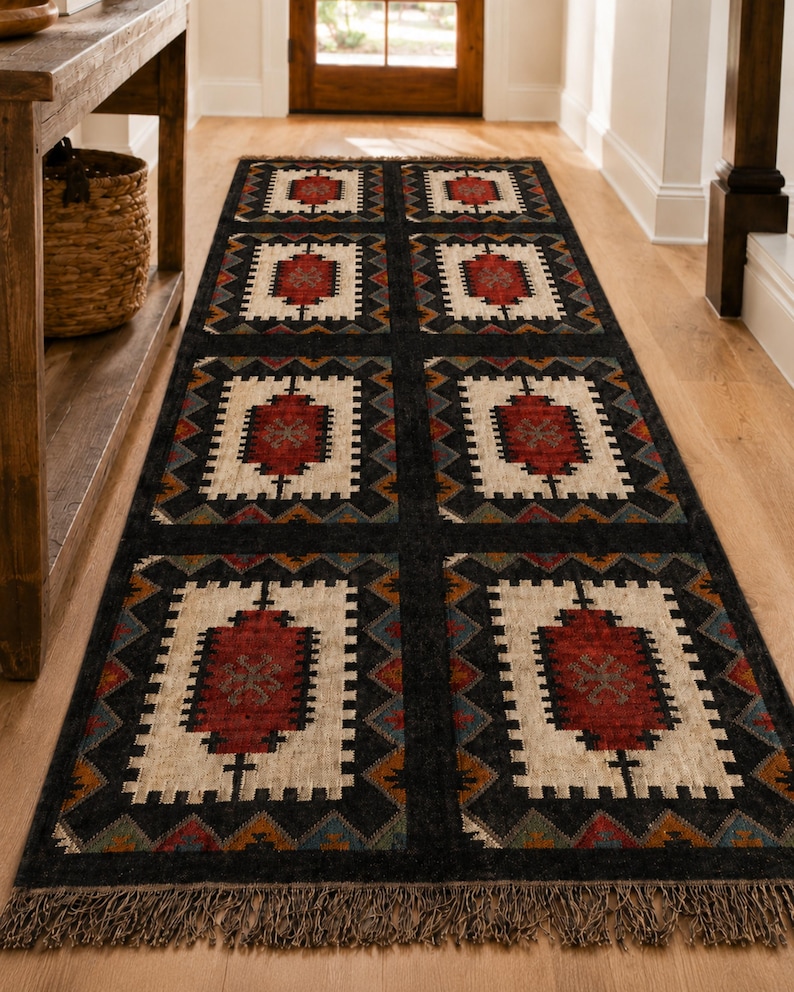 Overhead shot of black geometric dhurrie rug with repeating tribal square medallions in ivory rust and teal, natural fringe edges, custom size