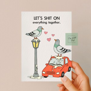 Pode incluir: Um cart&atilde;o de felicita&ccedil;&otilde;es humor&iacute;stico com o texto "LET'S SHIT ON everything together." apresenta dois pombos de desenho animado, um numa l&acirc;mpada e outro num carro vermelho. Cora&ccedil;&otilde;es cor-de-rosa flutuam no ar. O log&oacute;tipo The Wild Post est&aacute; no canto.