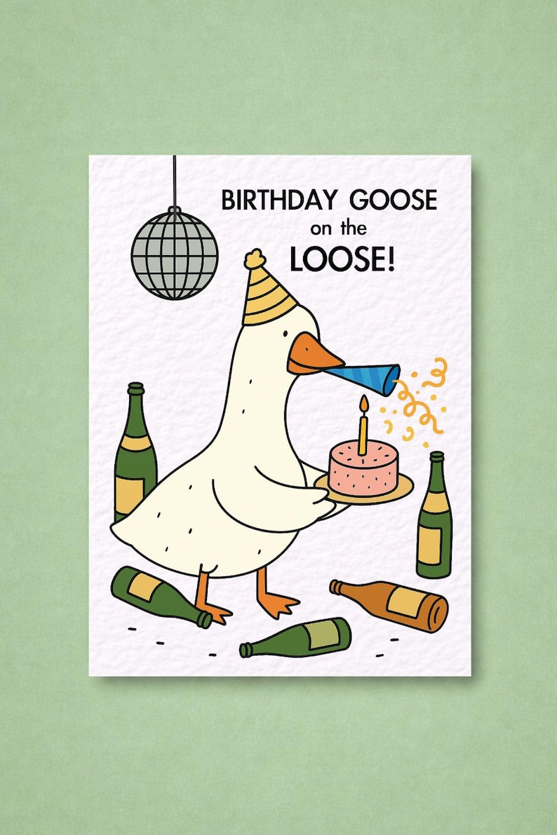 May include: A birthday greeting card featuring a cartoon goose wearing a party hat and holding a cake with a lit candle. The card has the text "BIRTHDAY GOOSE on the LOOSE!" and is surrounded by bottles.