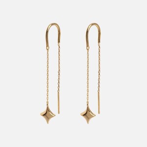 Puede incluir: Un par de pendientes colgantes dorados. Cada pendiente presenta una parte superior curvada, una delicada cadena y un dije en forma de estrella de cuatro puntas. Fondo blanco.