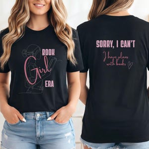 Könnte beinhalten: Schwarzes T-Shirt mit rosa Aufschrift "BOOK Girl ERA" und einer Strichzeichnung einer lesenden Person. Auf der Rückseite des T-Shirts steht "SORRY, I CAN'T I have plans with books" in Rosa.