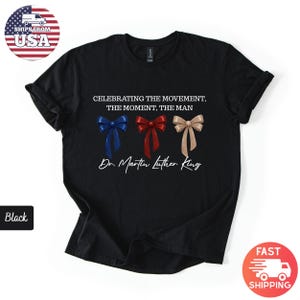 Peut inclure: T-shirt noir avec l'inscription "CELEBRATING THE MOVEMENT, THE MOMENT, THE MAN" et "Dr. Martin Luther King". Le motif comprend trois n&oelig;uds papillon bleus, rouges et beiges. Le t-shirt a un col rond classique.
