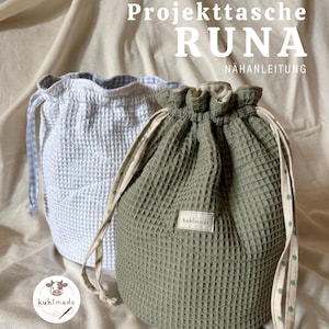 Op de afbeelding: Twee trekkoordtassen van textiel. Eén is lichtblauw, de andere olijfgroen. De tassen hebben een wafelachtig patroon en zijn voorzien van de tekst "Projektasche RUNA" en "NAHANLEITUNG". De tassen hebben trekkoorden met stippen.