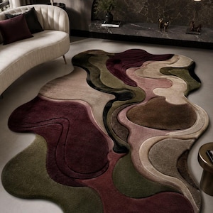 Può includere: Un tappeto dalla forma organica irregolare caratterizzato da un design topografico a strati. La superficie presenta una palette di toni bordeaux intenso, verde oliva, marrone tenue e beige delicato con sezioni intagliate e tridimensionali.