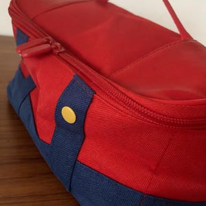 Könnte beinhalten: Ein Set aus drei Keramikbechern mit einer gesprenkelten, cremefarbenen Glasur. Jeder Becher hat ein anderes handgemaltes Design: ein blaues und grünes Blatt, eine gelbe Blume und eine rote Beere. Die Becher haben ein schlichtes, modernes Design.