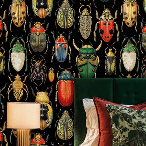 Beetle wallpaper in a stylish bedroom with green velvet headboard, rust and botanical pillows, and warm bedside lighting. The vintage entomology mural adds depth and artistic character to the room.
