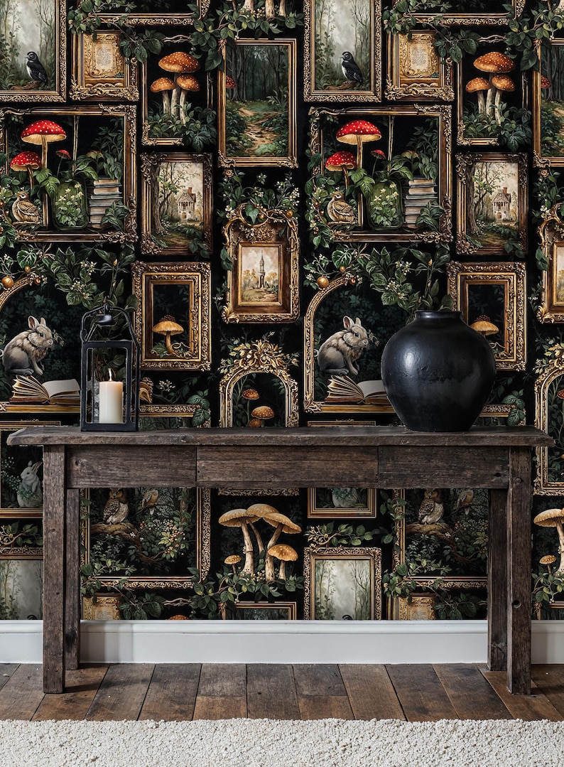 Moody dark academia wallpaper with ornate framed forest art and mushrooms styled behind a wooden console table with candle and ceramic decor, creating a dramatic vintage interior vignette.
