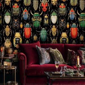 Vintage beetle insect wallpaper behind a deep red velvet sofa with patterned cushions and golden accents. The dark entomology mural creates a rich, moody atmosphere with natural history elegance.