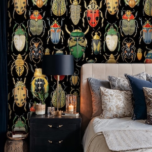 Colorful beetle wallpaper in a cozy bedroom with dark wooden nightstand, brass lamp, and soft beige bedding. The detailed insect illustration wall mural adds an elegant entomology-inspired touch to the interior decor.