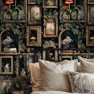 Dark academia gallery wallpaper featuring vintage gold frames, forest illustrations, mushrooms, and rabbits behind a cozy neutral bed with layered pillows, creating a moody gothic cottagecore bedroom atmosphere.