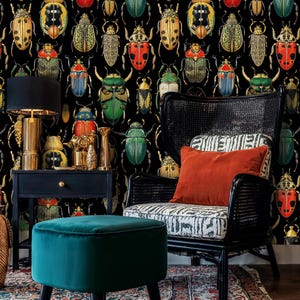 Dark beetle wallpaper with vibrant insect illustrations creating a dramatic backdrop for a reading corner featuring a teal velvet ottoman and wicker chair. A perfect blend of art deco and vintage style.