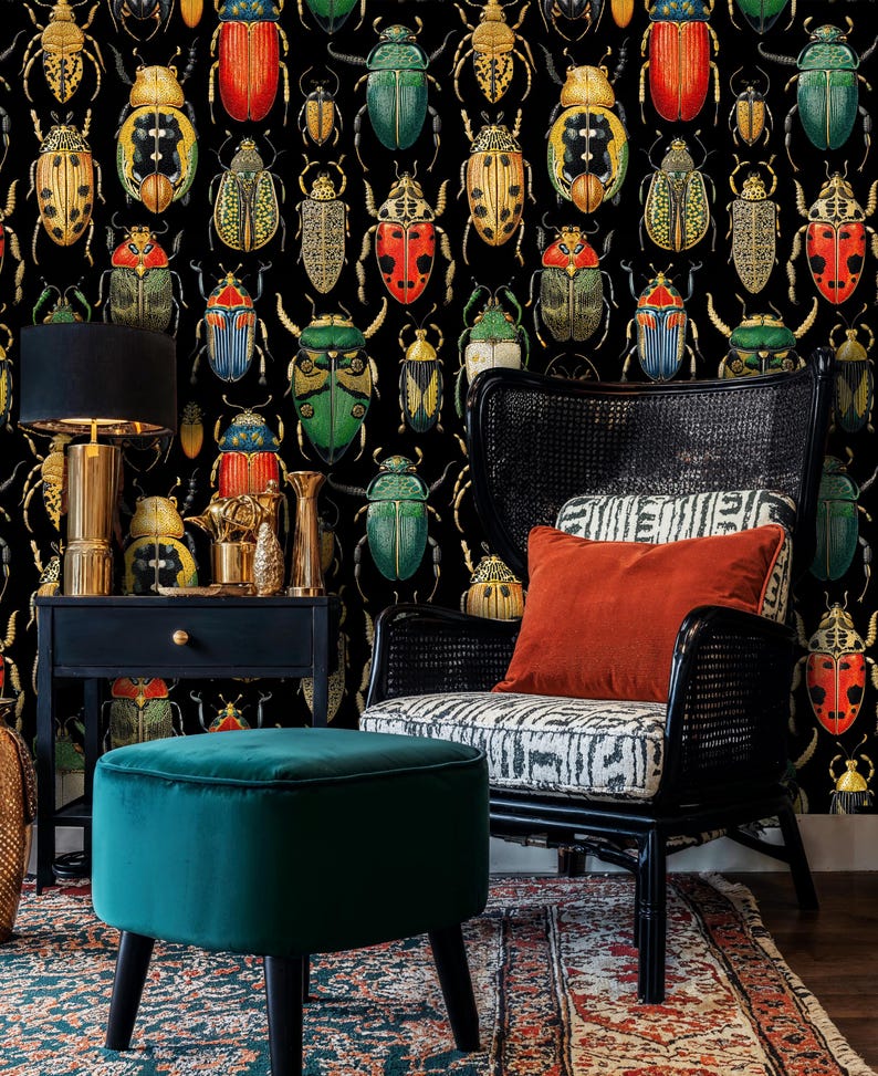 Dark beetle wallpaper with vibrant insect illustrations creating a dramatic backdrop for a reading corner featuring a teal velvet ottoman and wicker chair. A perfect blend of art deco and vintage style.