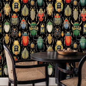 Colorful beetle wallpaper behind a small dining table with rattan chairs and wooden accents. The insect illustration mural adds personality and museum-style charm to the cozy dining space.