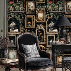 Gothic gallery wall wallpaper featuring antique frames, rabbits, and woodland details behind a vintage armchair and side table, forming a cozy dark academia reading corner.