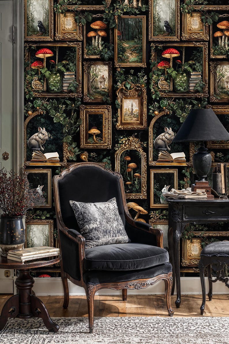 Gothic gallery wall wallpaper featuring antique frames, rabbits, and woodland details behind a vintage armchair and side table, forming a cozy dark academia reading corner.