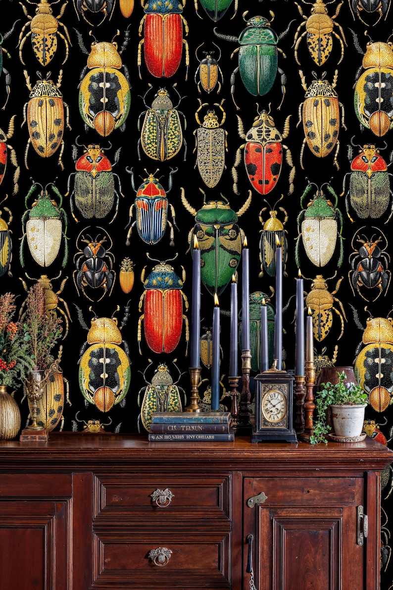 Artistic beetle illustration wall mural featuring colorful insects on black background, styled with antique wooden console, candles, and vintage books for a classic natural history interior.