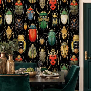 Dark beetle wallpaper in an elegant dining room with green velvet chairs, gold vases, and a dark wood table. The insect mural brings a bold, artistic, and eclectic statement to the space.
