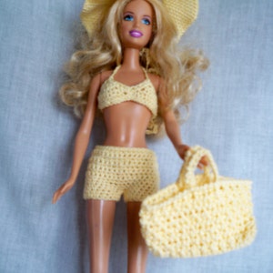 May include: A yellow crocheted swimsuit with a matching hat and tote bag. The swimsuit has a halter top and shorts. The hat has a wide brim. The tote bag has a single handle.