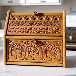 May include: A rectangular wooden bread box featuring intricate hand-carved geometric and floral patterns. The front panel displays symmetrical scrollwork and circular motifs, while the slanted top lid showcases repeating triangular and arched designs.