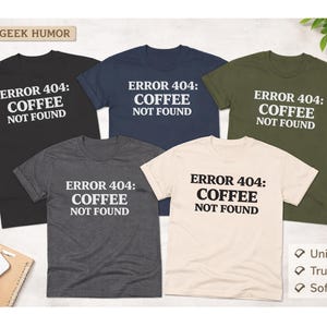 May include: Five short-sleeved t-shirts in black, navy, olive green, charcoal gray, and cream. Each shirt features the text "ERROR 404: COFFEE NOT FOUND" in bold white letters. The shirts are labeled as unisex, true to size, and made of soft cotton.