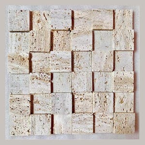 May include: A square, textured tile mosaic with a 3D effect. The tiles are a light beige color with darker beige and brown speckles. The mosaic is made of natural stone and has a rough, porous surface.