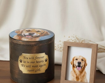 May include: A wooden pet urn with a golden retriever image on the lid and a framed photo of a golden retriever. The urn has a gold plaque with the text "You will forever be in our hearts. We will meet again sweet girl."