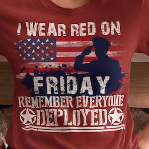 May include: Maroon crew neck t-shirt with the text "I Wear Red on Friday Remember Everyone Deployed" and an American flag graphic. The graphic also includes a silhouette of a saluting soldier.