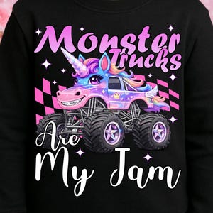 Puede incluir: Sudadera negra con un gr&aacute;fico colorido de un cami&oacute;n monstruo unicornio y el texto "Monster Trucks Are My Jam". El cami&oacute;n tiene un cuerno, alas y una cara sonriente. El dise&ntilde;o incluye detalles a cuadros rosas y blancos.