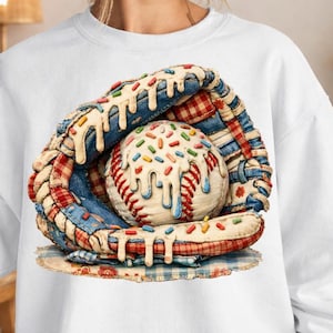 Puede incluir: Sudadera blanca con un guante de béisbol y una pelota de béisbol diseñada para parecerse a un postre. El guante tiene detalles de patchwork rojos, blancos y azules. La pelota de béisbol está cubierta de chispas y glaseado goteando.