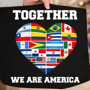 May include: Black tote bag with the words "TOGETHER" and "WE ARE AMERICA" in white. A heart shape in the center is filled with various national flags. The bag is held by a person.